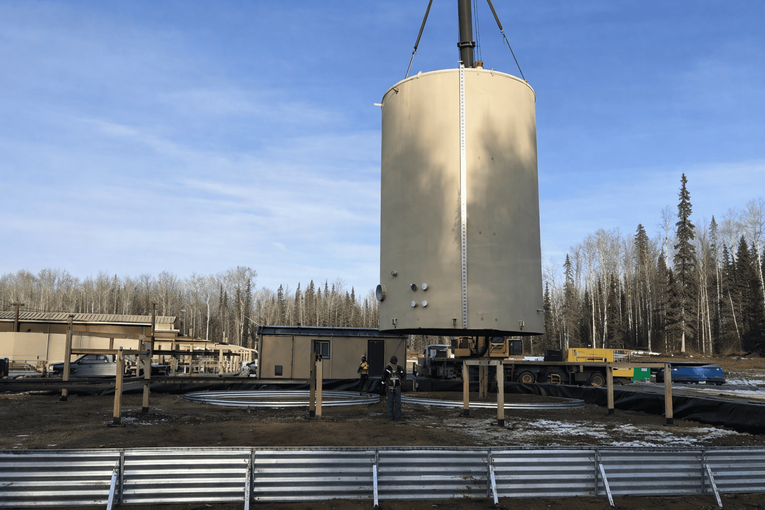 Oil storage tank installation at upstream production facility Crane lifting oil storage tank