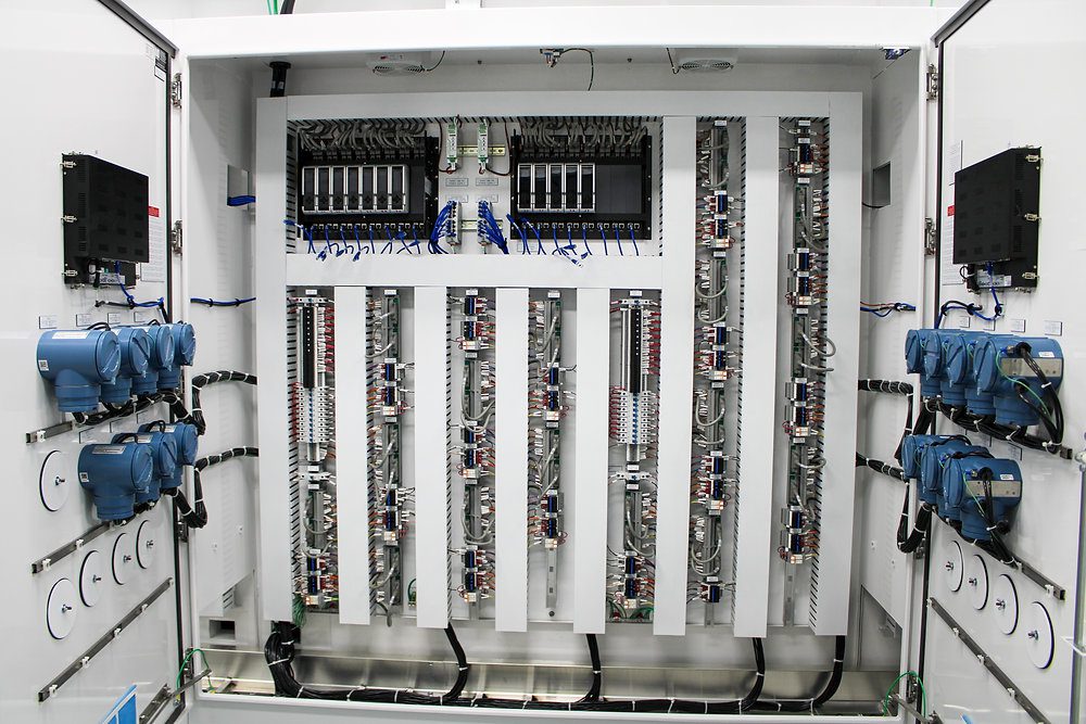 PLC Programming & Industrial Automation Services Technician working inside a PLC control cabinet with input and output modules